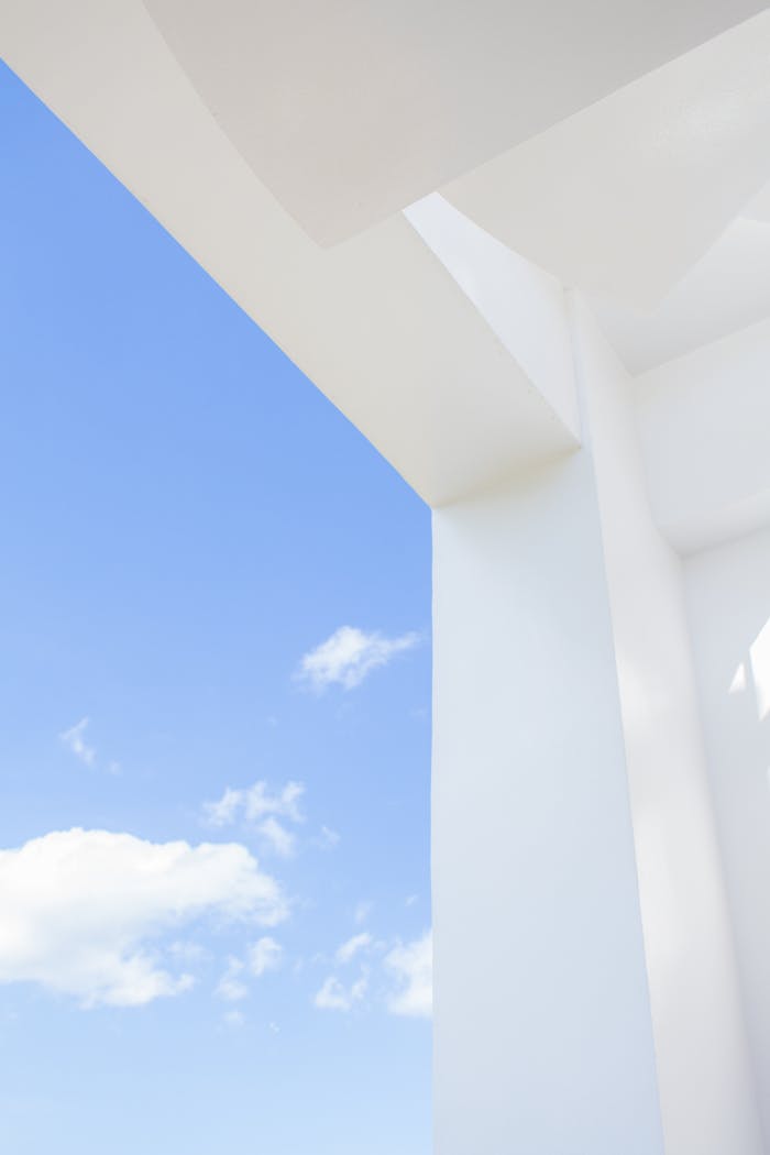 Sleek white structure with blue sky and clouds, showing minimalist architectural design elements.